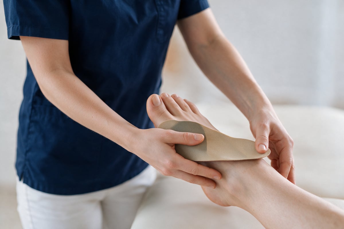 Arzt erklärt einer Patientin eine orthopädische Einlage.
