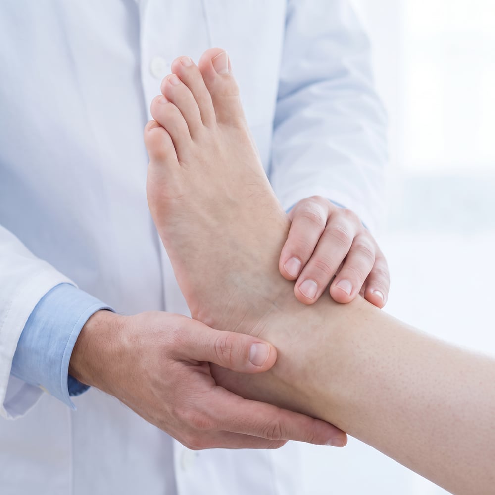 Arzt untersucht Fuß und Sprunggelenk einer Patientin